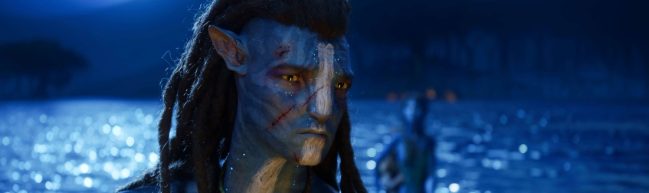 Filmstill aus Avatar: The Way of Water: Portrait von Jake (Sam Worthington) mit Schnittwunden im Gesicht, ernster Blick, im Hintergrund das Meer. Es ist Nacht.