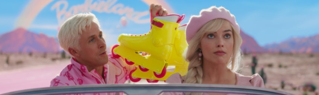 Barbie fährt im Cabrio, schräg hinter ihr sitzt Ken. Alles ist rosa, beide haben hellblonde Haare.